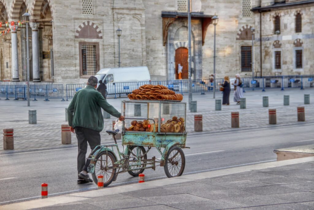 Street vendor with a cart full of simit in front of a historic mosque.