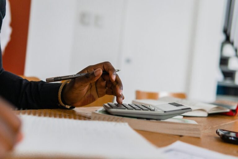 A Person Using a Calculator While Holding a Pen